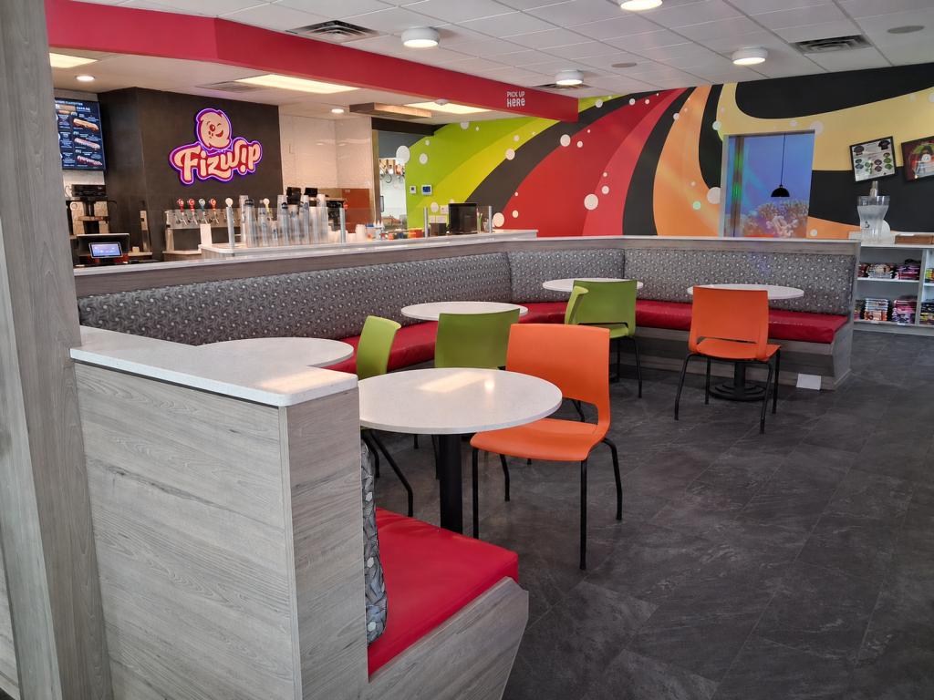 Contemporary quick-service restaurant interior featuring branded environmental graphics, modern booth seating, and customer-focused commercial interior design.